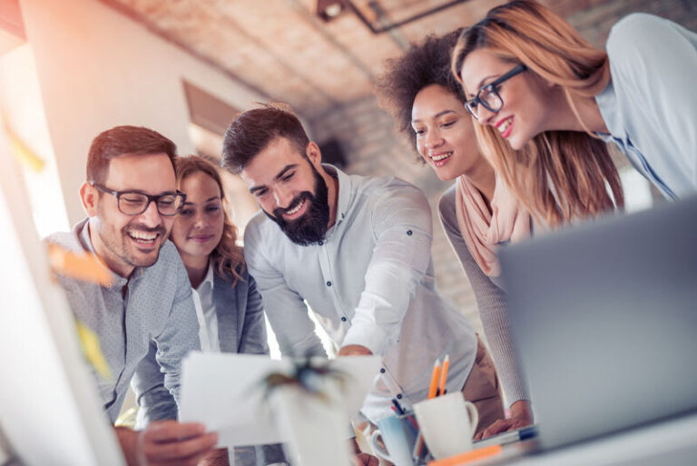 Fünf junge Mitarbeiter arbeiten zusammen an einm Projekt im Büro.